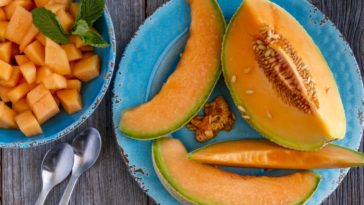 A plate of sliced cantaloupes on a wooden table.