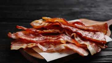 Slices of crispy fried bacon on a chopping board.