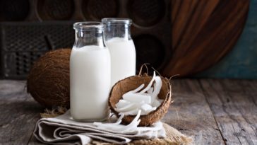 A couple of bottle of coconut milk with fresh coconuts.